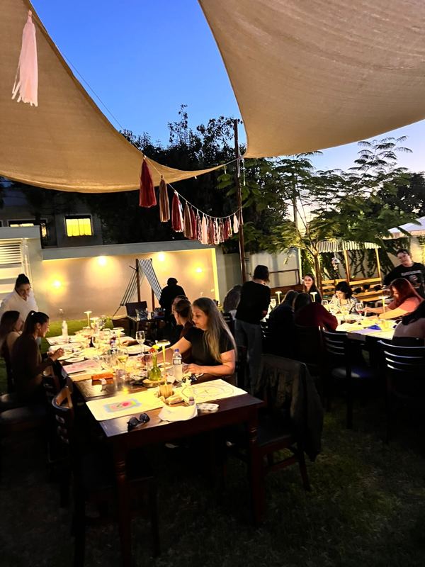 Jantar entre amigos no jardim do Festou sob vela de sombra e luzinhas