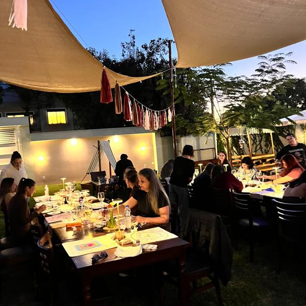 Jantar entre amigos no jardim do Festou sob vela de sombra e luzinhas
