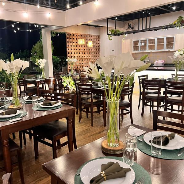 Salão do Festou à noite preparado para casamento, com mesas de madeira, lírios e luzes de varal, em Realeza PR